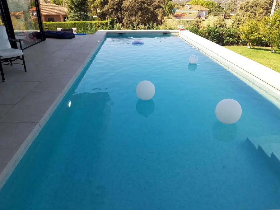 Piscina rectangular con bolas de luz, junto a la terraza de la vivienda