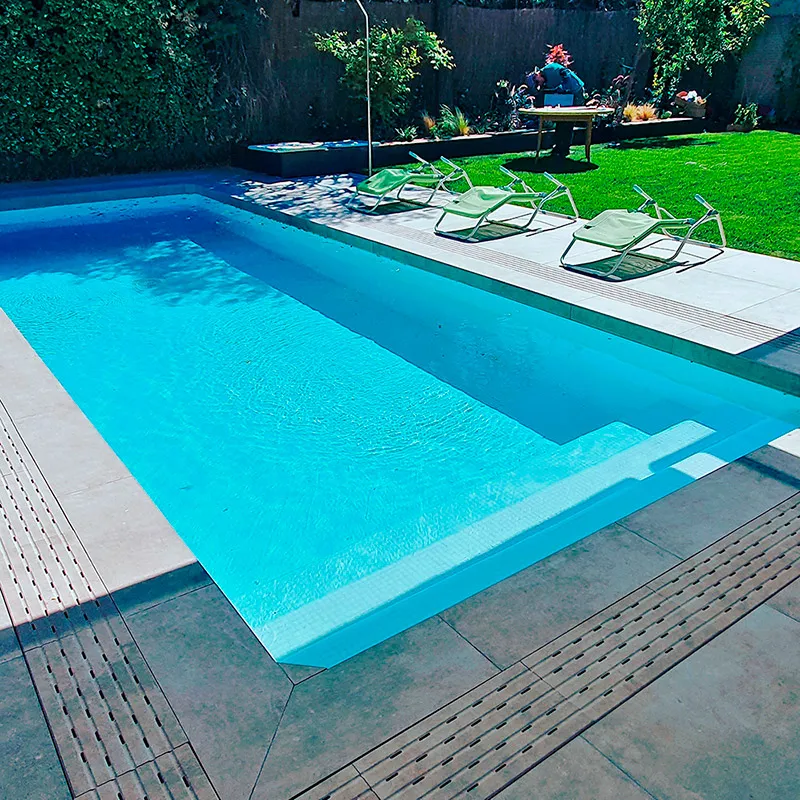 Piscina con solárium de piedra, tumbonas y césped