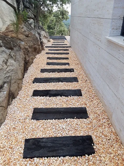 Losas oscuras sobre grava blanca en el acceso de la vivienda